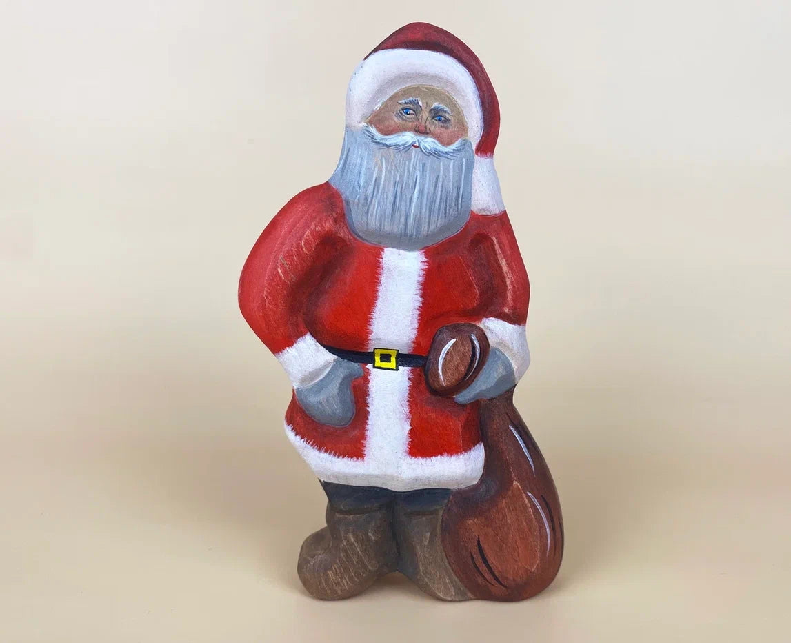 Wooden santa claus toy in red Christmas robes, Christmas hat and carrying a brown bag of presents!